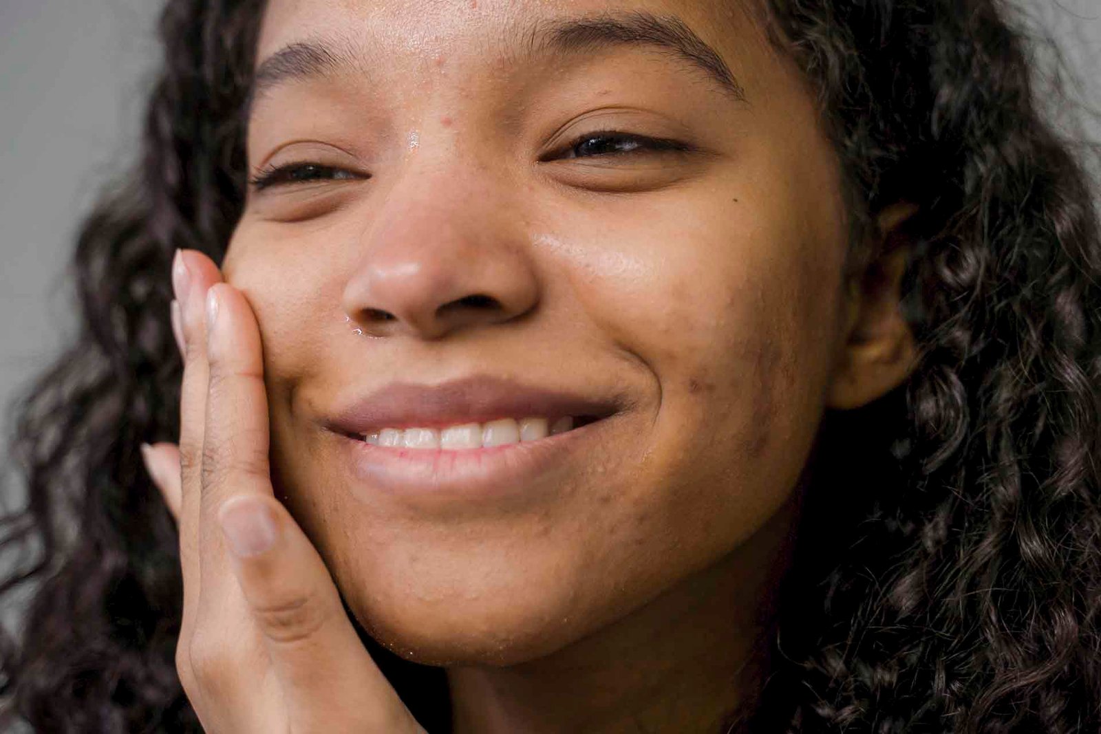 Plano fechado de uma moça com a mão no rosto, sorrindo